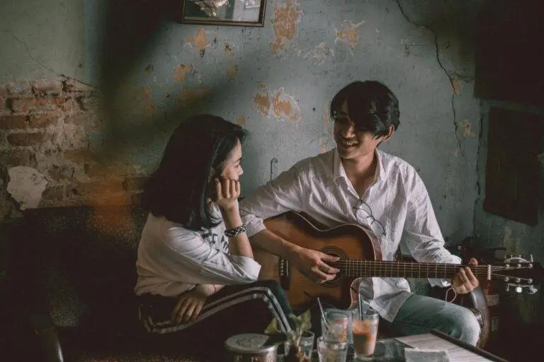A couple enjoys an intimate music session indoors with a guitar.