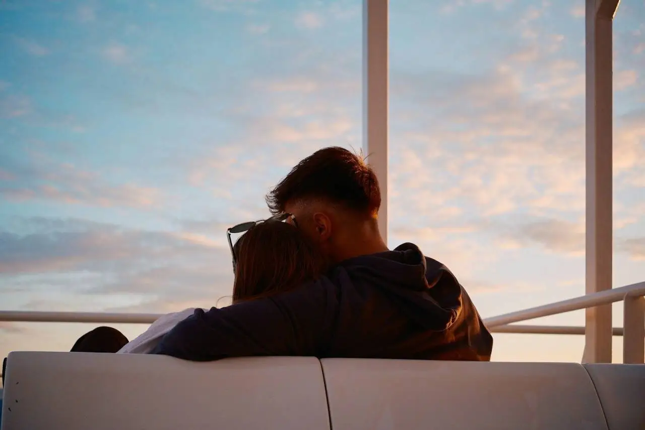 A couple embraces while watching the sunset.