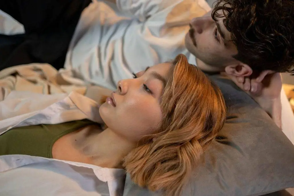 A serene couple lying together indoors, expressing intimacy and relaxation.
