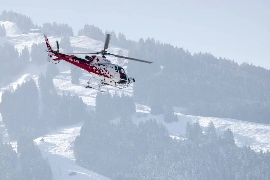 A helicopter soars over the snow-covered Swiss Alps in winter, showcasing stunning alpine scenery.