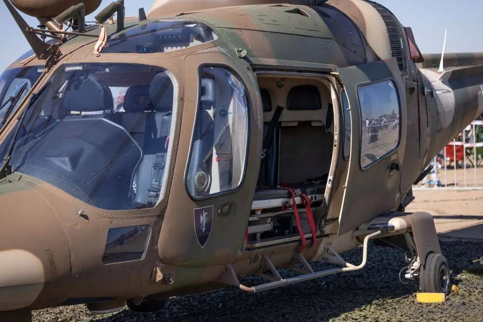Close-up of a military helicopter with an open door on display at an outdoor event, showcasing its interior.